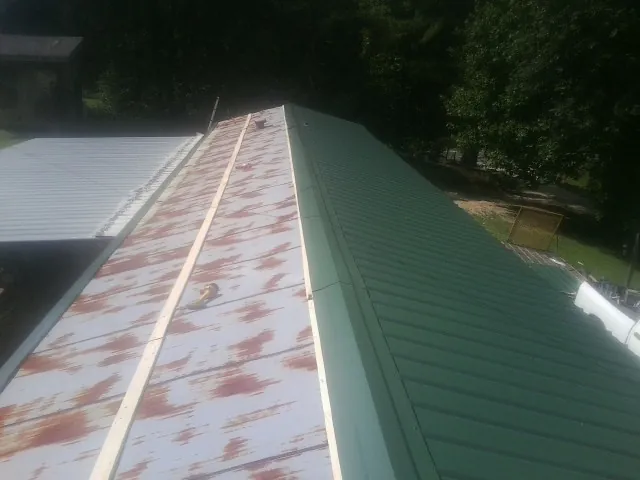 Old rusted panels beside newly installed green metal roofing — Wind Damage Roof Repair by Roofing Brothers in Freeman