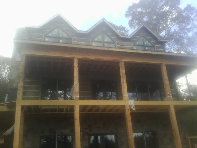 Dormers and porch framing on a large log home under construction — Roof Coating work by our crew in Freeman