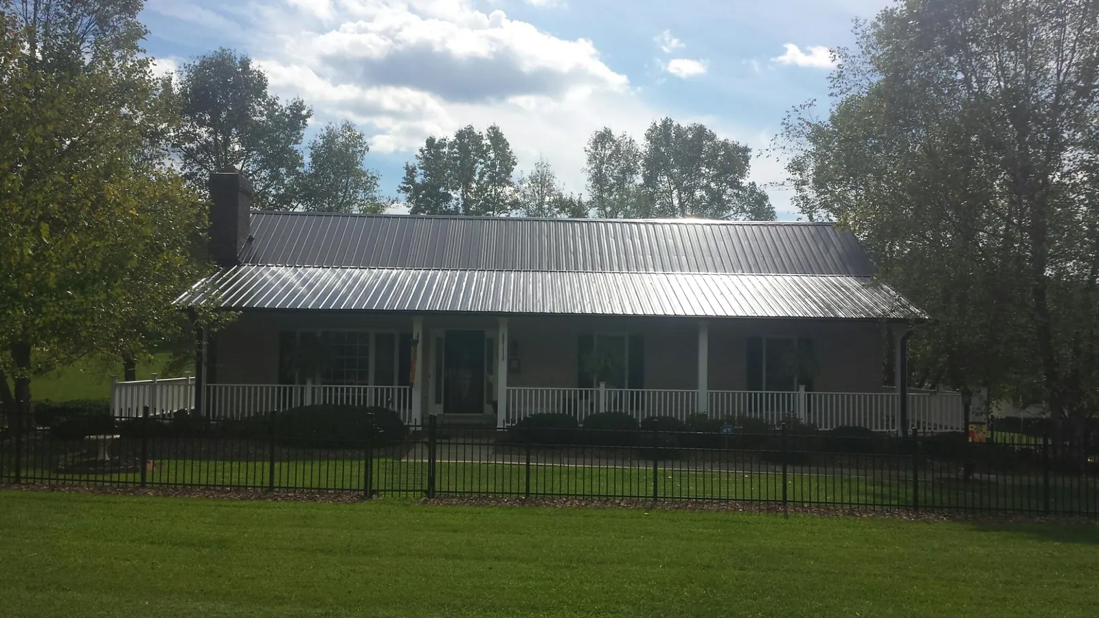 Gray metal roof on a brick ranch with a full width front porch — Gutter Guard Installation work by our crew in Freeman